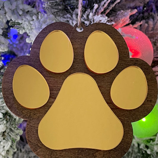 Dog Paw ornament hanging on Christmas Tree. The ornament is wooden, the dog paw is mirror gold.